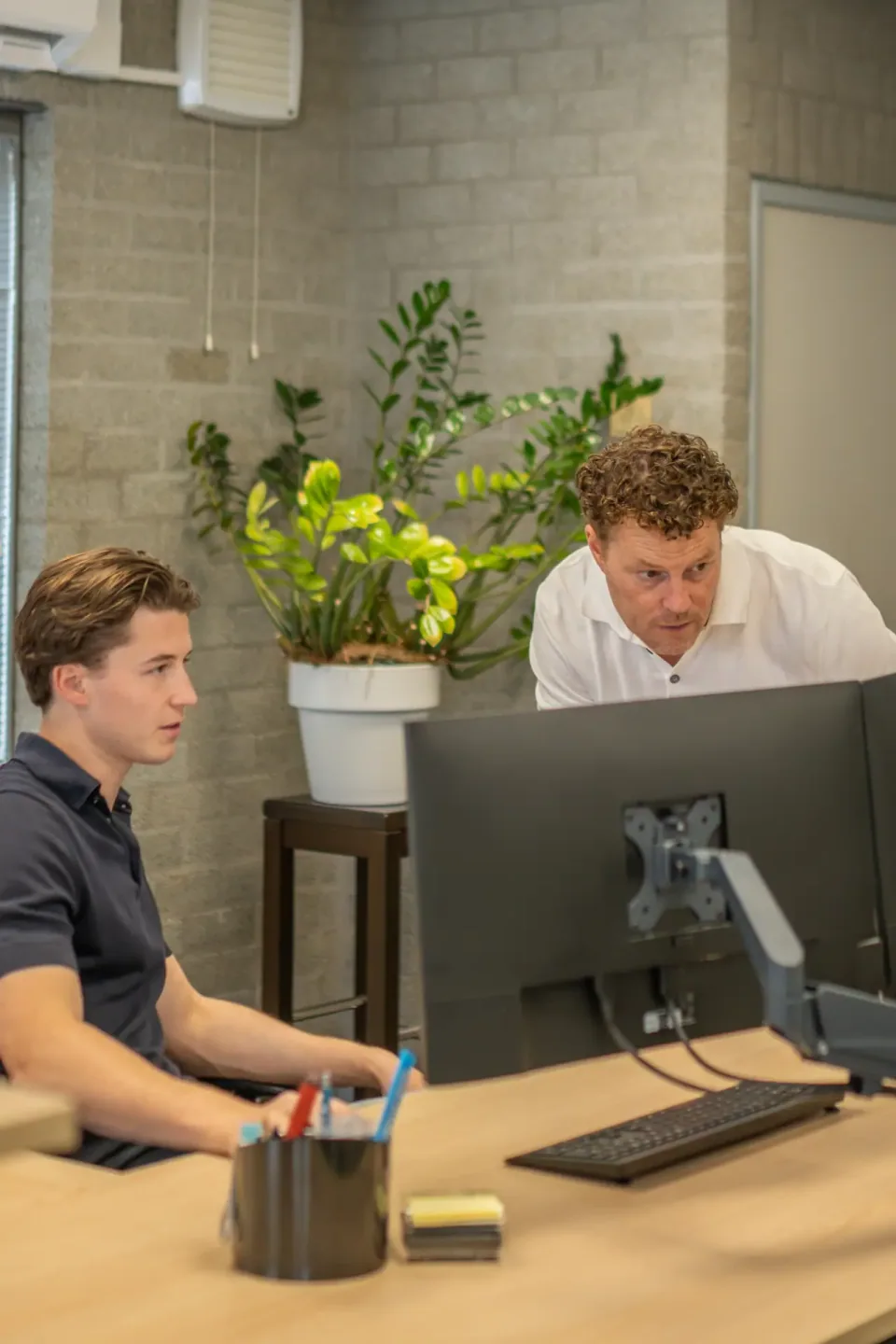 Twee collega's van E-Charging achter het beheerscherm op kantoor